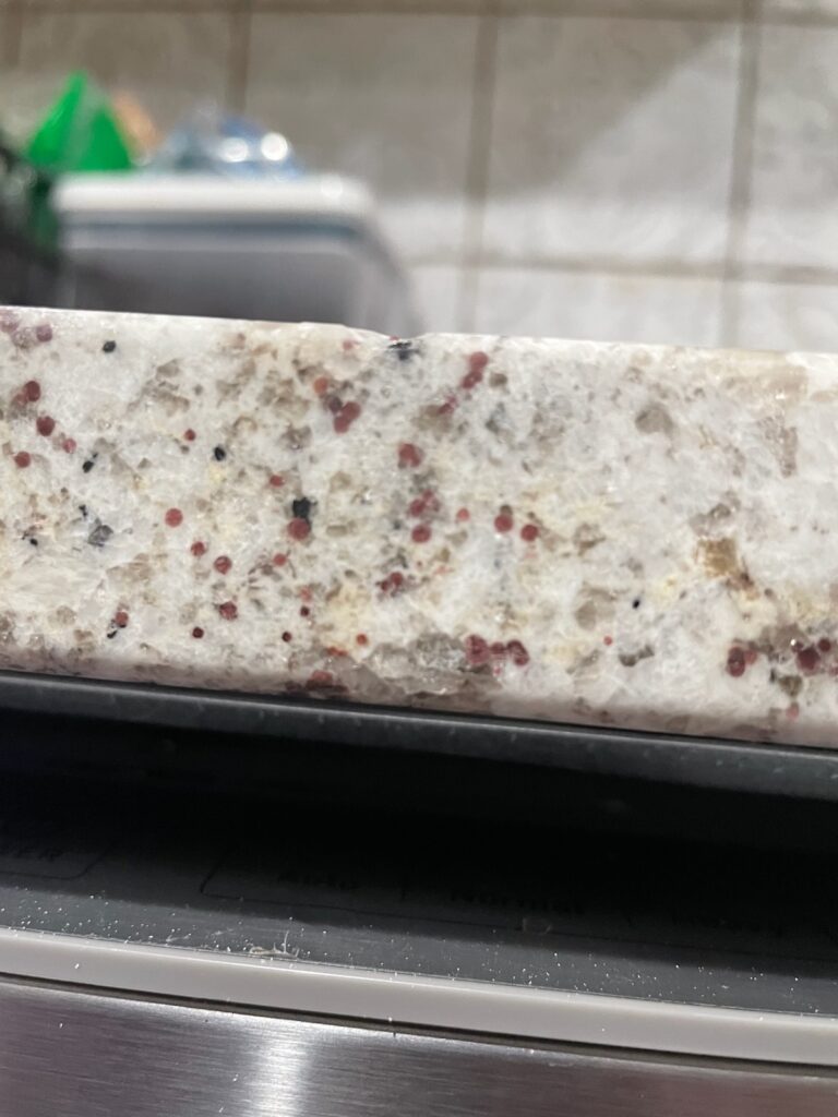 A granite countertop chip prior to being repaired by a Tops Solid Surface service technician. Puget Sound Area.