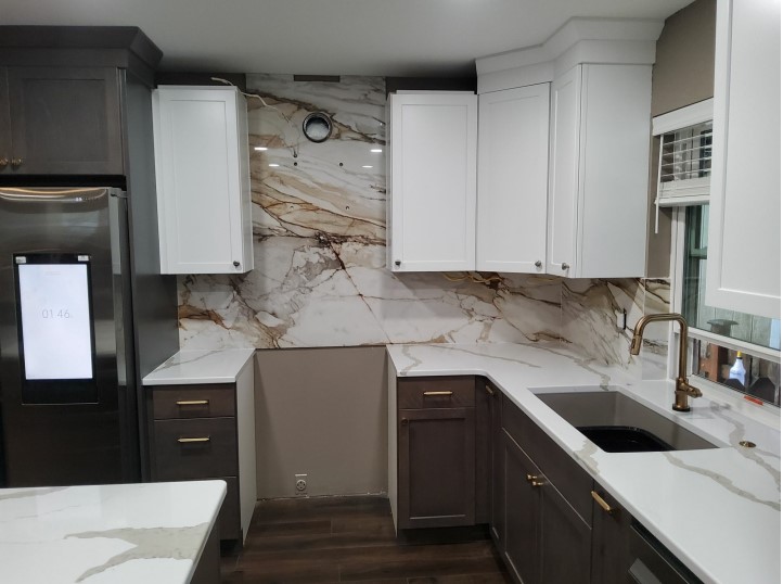 A quartz kitchen with a custom porcelain slab backsplash to accent the brown cabinetry